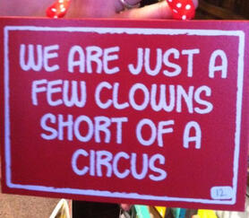 A red sign. The signs text reads "We are just a few clowns short of a circus"